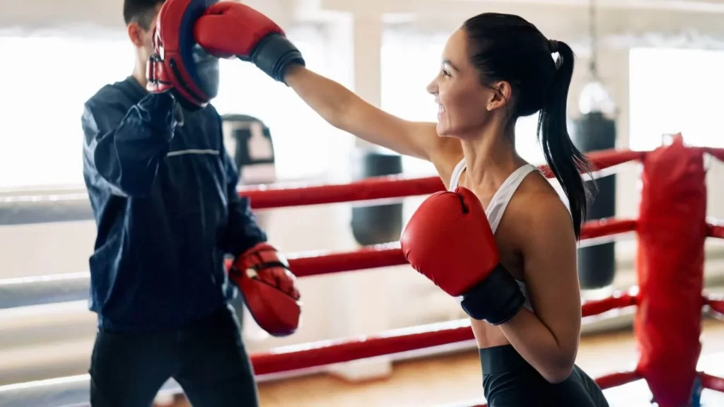 Image-of-a-woman-practicing-mitts-with-a-trainer-in-a-gym.