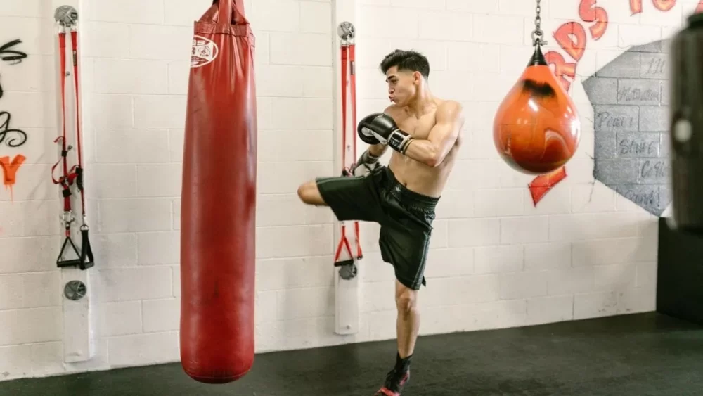 Image-of-a-man-practicing-a-right-middle-kick-with-a-sandbag